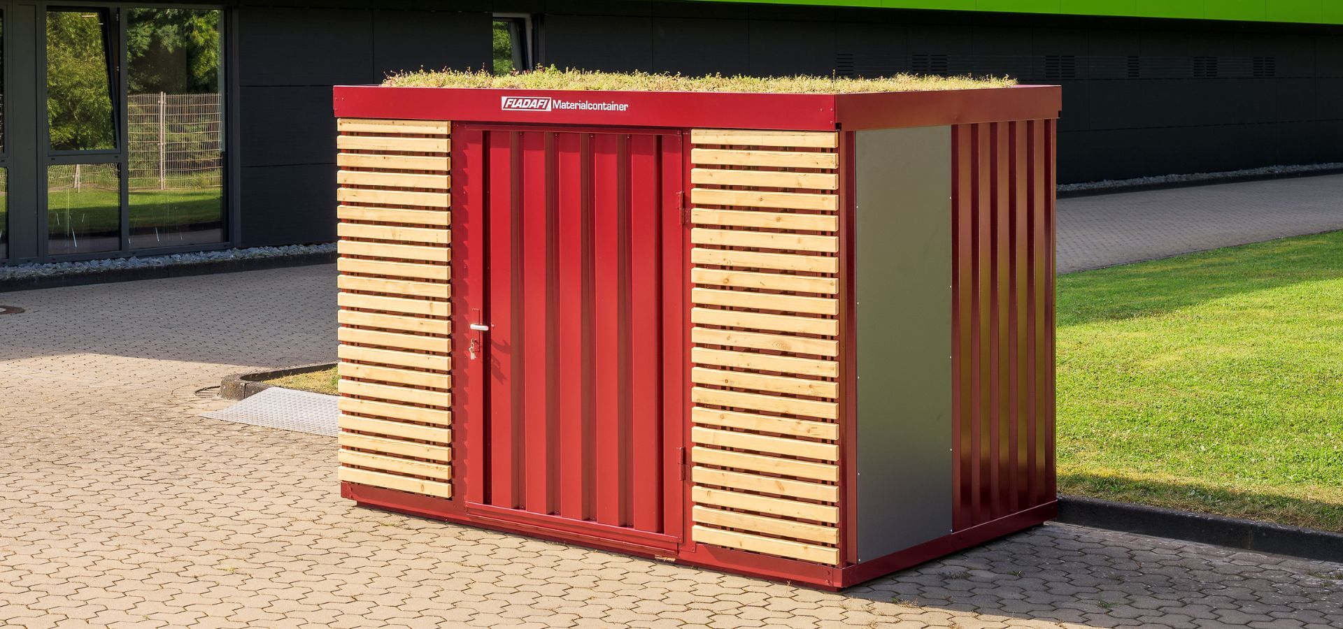 Roter FLADAFI® Lagercontainer mit Holzfassade und Dachbegrünung